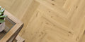 Wooden floor with herringbone pattern and a small plant on a wooden surface.