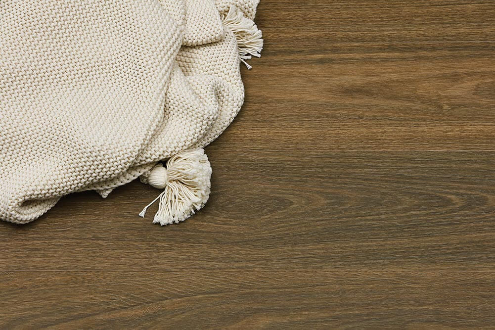Beige textured blanket with tassels on a wooden surface