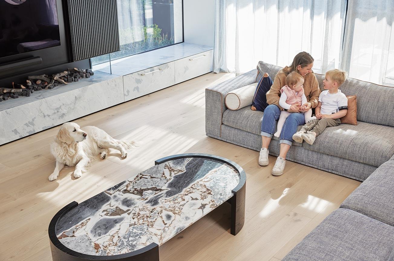 Family sitting on a couch in a modern living room with a dog.