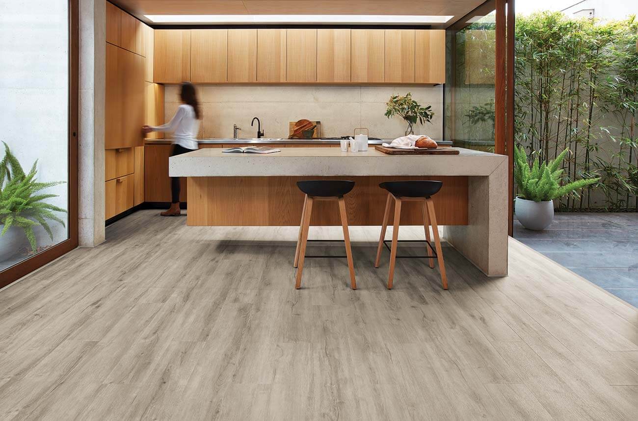 Modern kitchen with wooden cabinets and a woman preparing food.