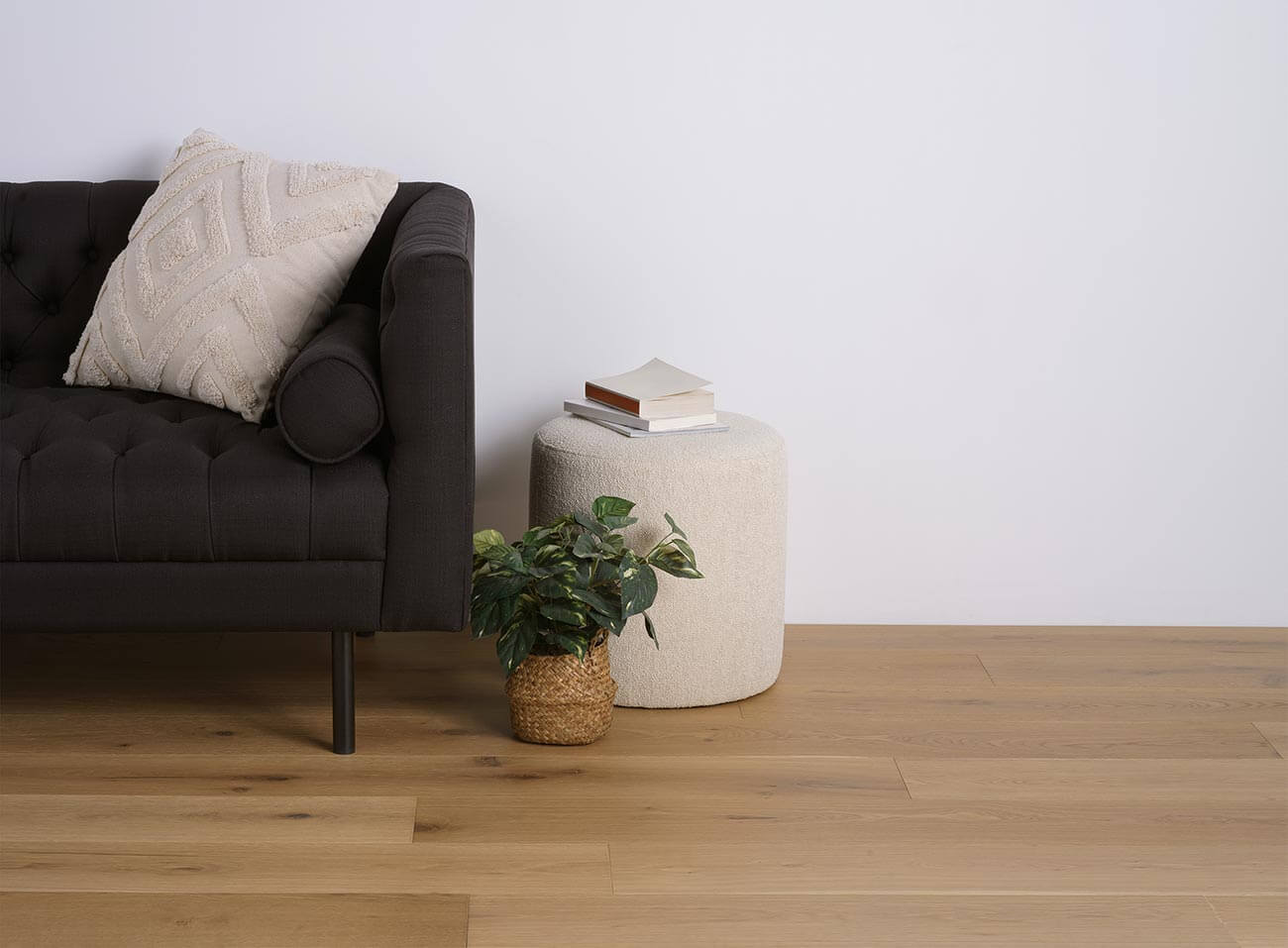 Modern living room with a dark gray sofa, small table, and plant on a wooden floor.