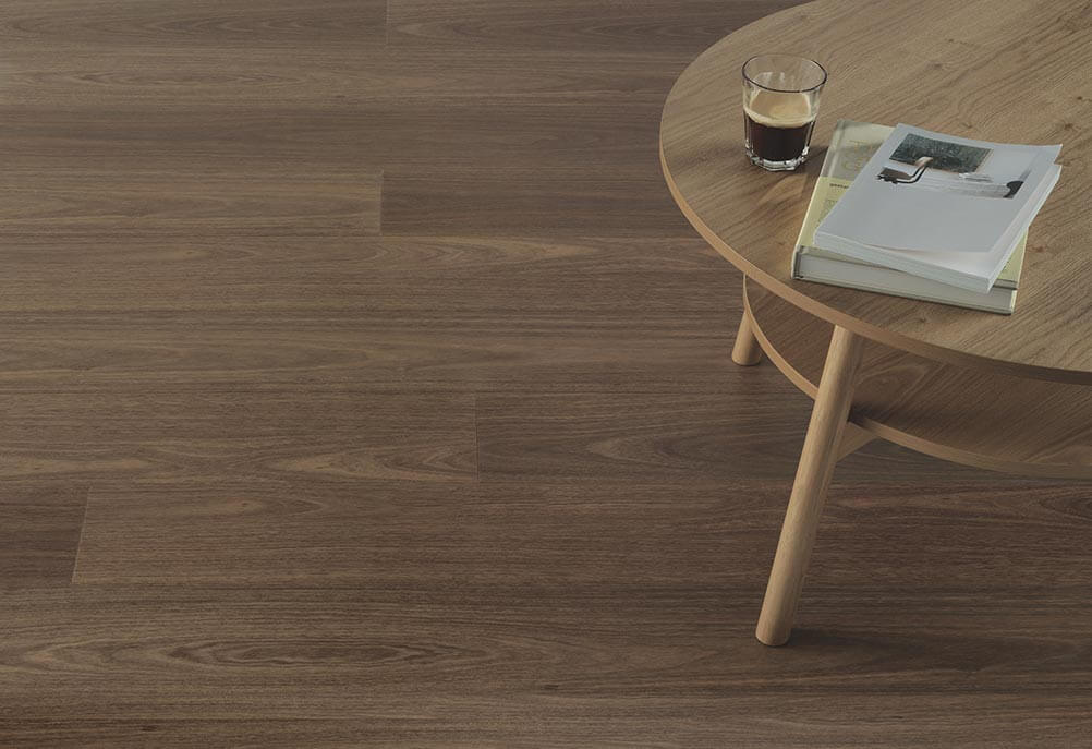 Wooden floor with a small round table and a glass of dark liquid on it.