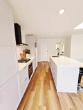 Modern kitchen with white cabinetry, wooden floor, and island.