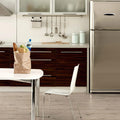 Modern kitchen with stainless steel refrigerator, wooden cabinets, and a small table with a bag.