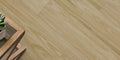 Close-up of a wooden floor with a small table and plant in the corner.