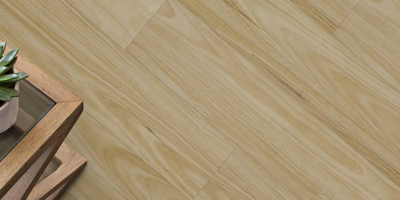 Close-up of a wooden floor with a small table and plant in the corner.