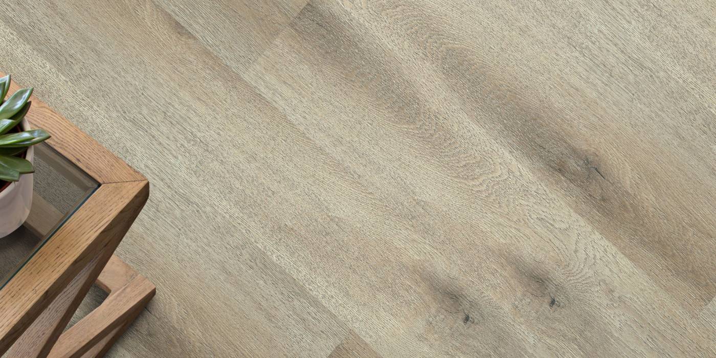 Close-up of a wooden floor with a small table and plant in the corner.
