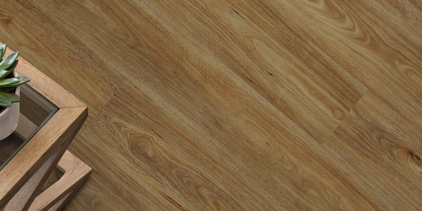 Close-up of a wooden floor with a plant on a table in the corner.