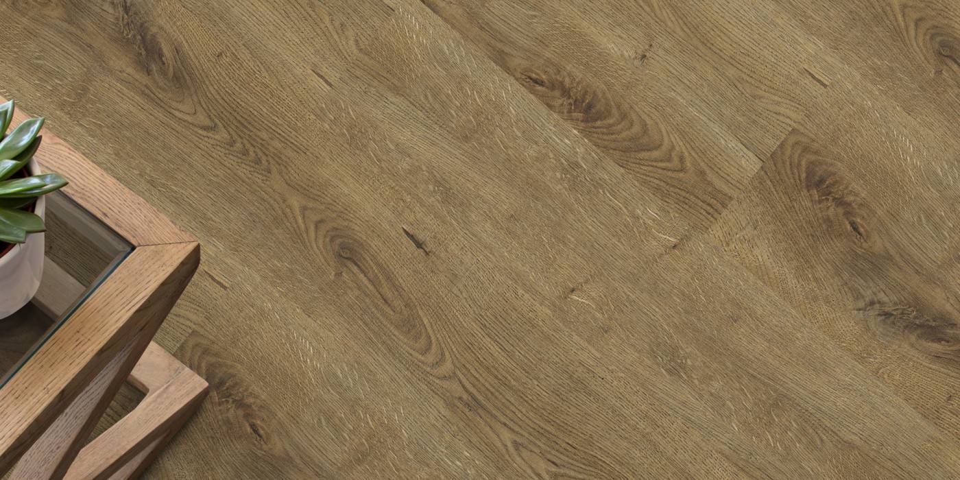 Close-up of wooden flooring with a plant and wooden furniture corner.