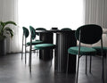 Dining table with green chairs in a room with curtains and a plant.